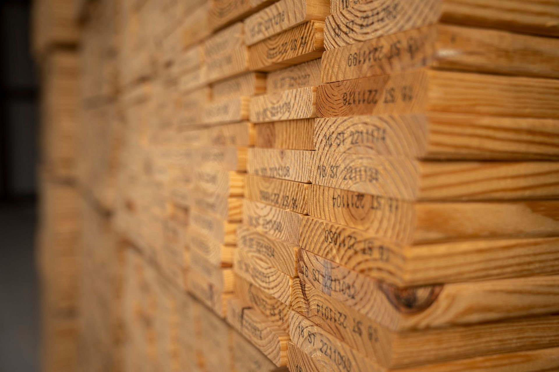 Detailed view of neatly stacked timber planks displaying texture and grain in a warehouse setting.
